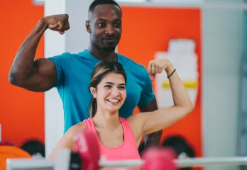 woman shows muscle with personal trainer