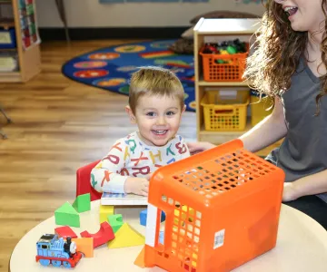 child playing with table toys with teacher