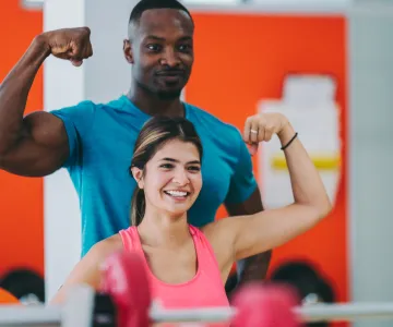 woman shows muscle with personal trainer