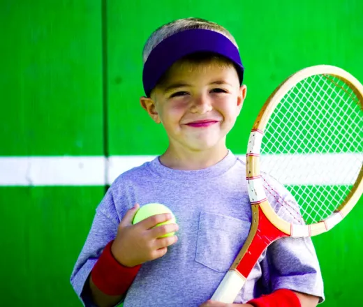 boy holding tennis ball and racket
